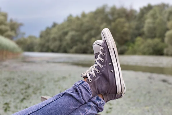 Pernas com tênis no lago — Fotografia de Stock