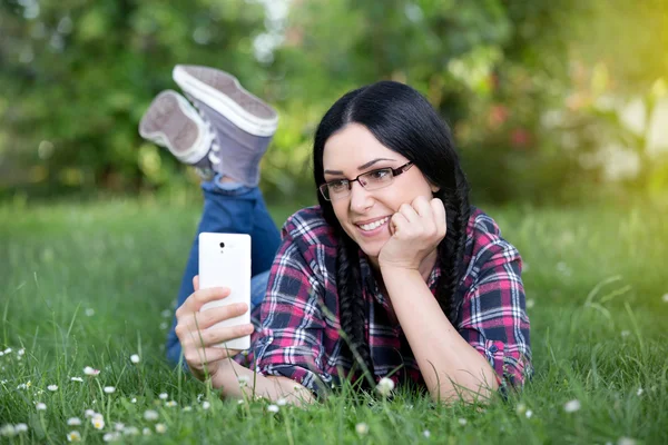 Girl texting on smart phone on grass — Stock Photo, Image