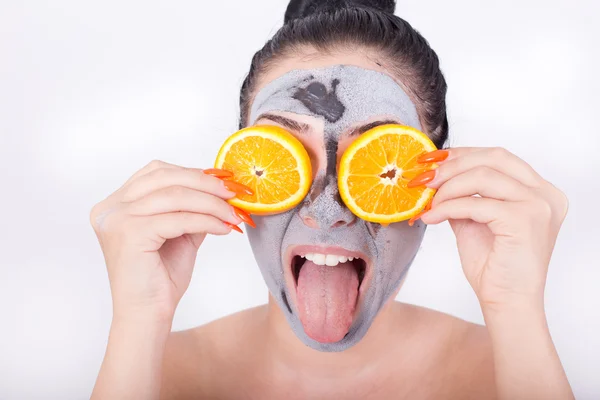 Menina com máscara facial e fatias de laranja — Fotografia de Stock