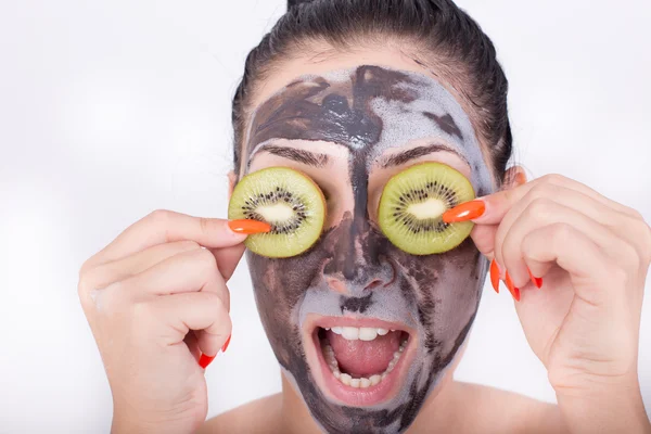 Menina com máscara facial e kiwi — Fotografia de Stock