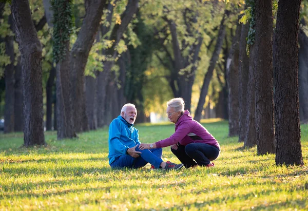 Senior Man Injured Knee Sitting Grass Pain Jogging Woman Taking — Stock Photo, Image