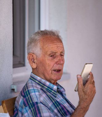 Video görüşmesi için cep telefonu kullanan kıdemli bir adamın portresi