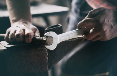 Atölyede eski İngiliz anahtarıyla çalışan erkeklerin ellerini kapatın.