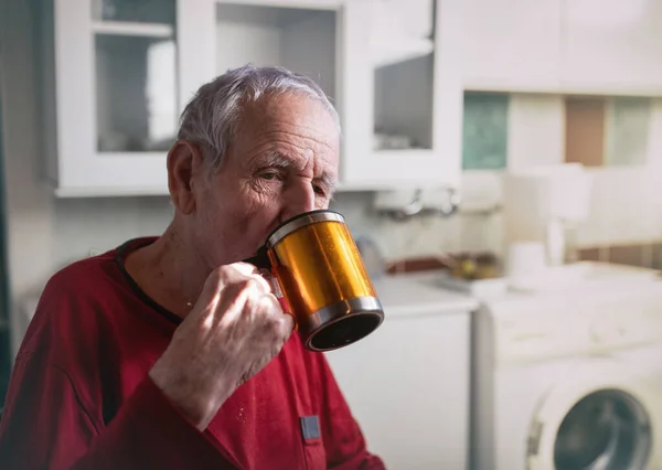 90多岁的老人在家里厨房里用杯子喝茶 — 图库照片