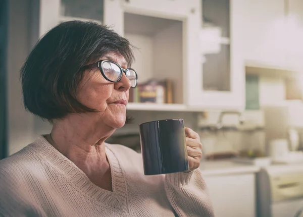 老年妇女在家里厨房的杯子里休息和喝热咖啡 — 图库照片