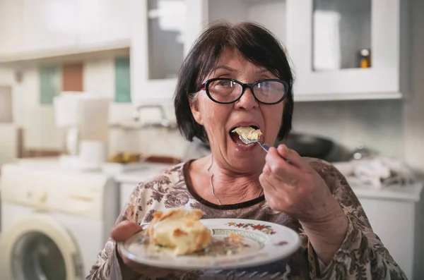 老婦人は夜には台所でおいしいケーキをかむために口を開けている お菓子の概念の過剰摂取と中毒 — ストック写真