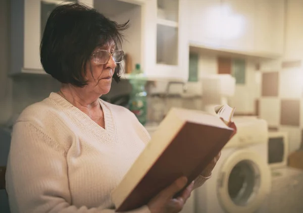 Seniorin Sitzt Waschküche Und Liest Buch — Stockfoto