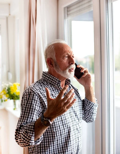 Senior Standing Next Window Looking Out Speaking Mobile Phone Upset — Stock Photo, Image