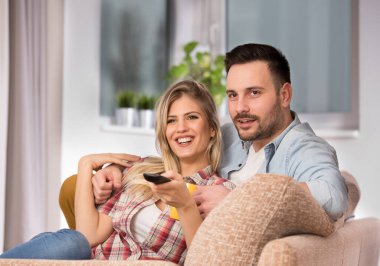 Birlikte televizyon izleyen genç ve çekici bir çift. Uzaktan kumandalı kadın.