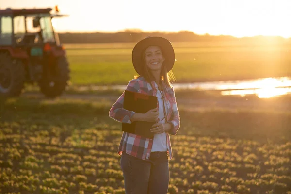 Mujer Joven Agricultora Mirando Cámara Campo Sujetando Portapapeles Agrónomo Pie — Foto de Stock