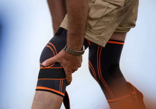 Hiker putting knee brace on. Injured leg and safety concept in recreation