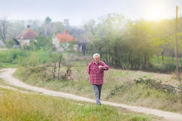 Senior man walkng in village — Stock Photo, Image