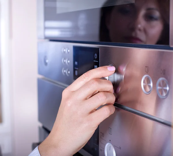 Female hand on oven knobs — Stock Photo, Image