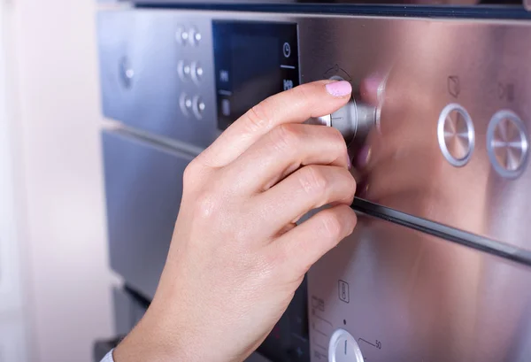 Mano femenina en perillas del horno — Foto de Stock