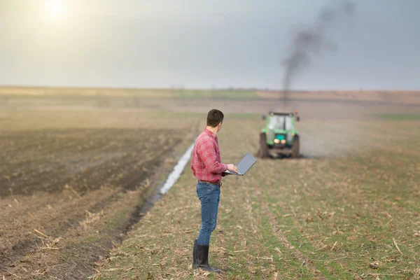 Фермер с ноутбуком и трактором — стоковое фото