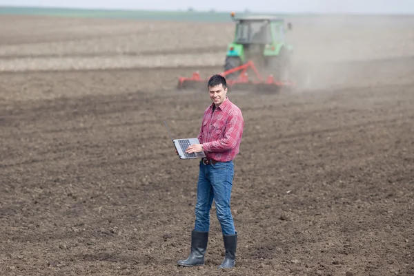 Boer met laptop en trekker — Stockfoto