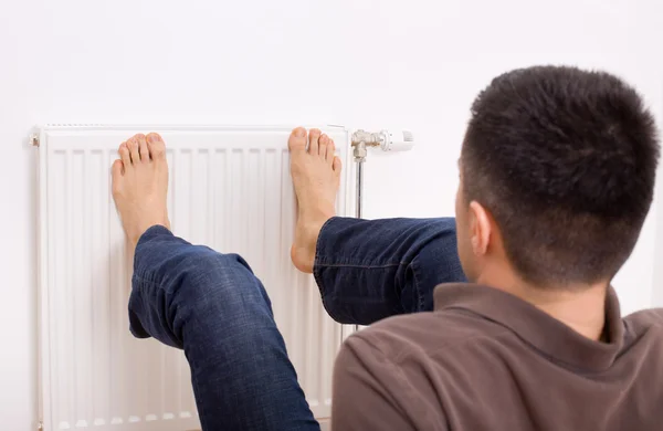 Man heating feet on radiator — Stock Photo, Image