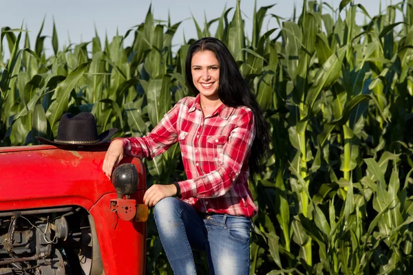 Woman sitting on tractor in field — Stock Photo, Image