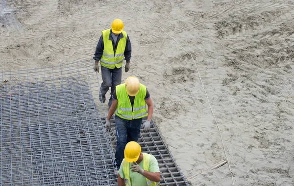 Trabalhadores da construção que transportam armadura — Fotografia de Stock