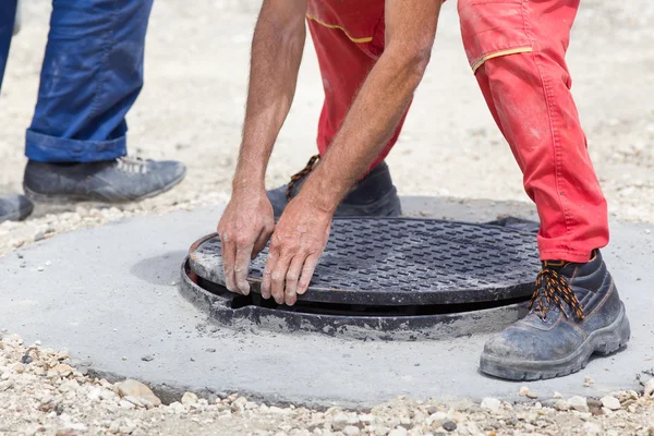 Arbeiter montiert Gullydeckel an Gullydeckel — Stockfoto