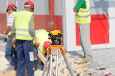 Teodolit ve inşaat sahasında işçiler