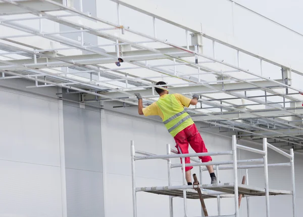 Worker painting awning on scaffolding — Stock Photo, Image