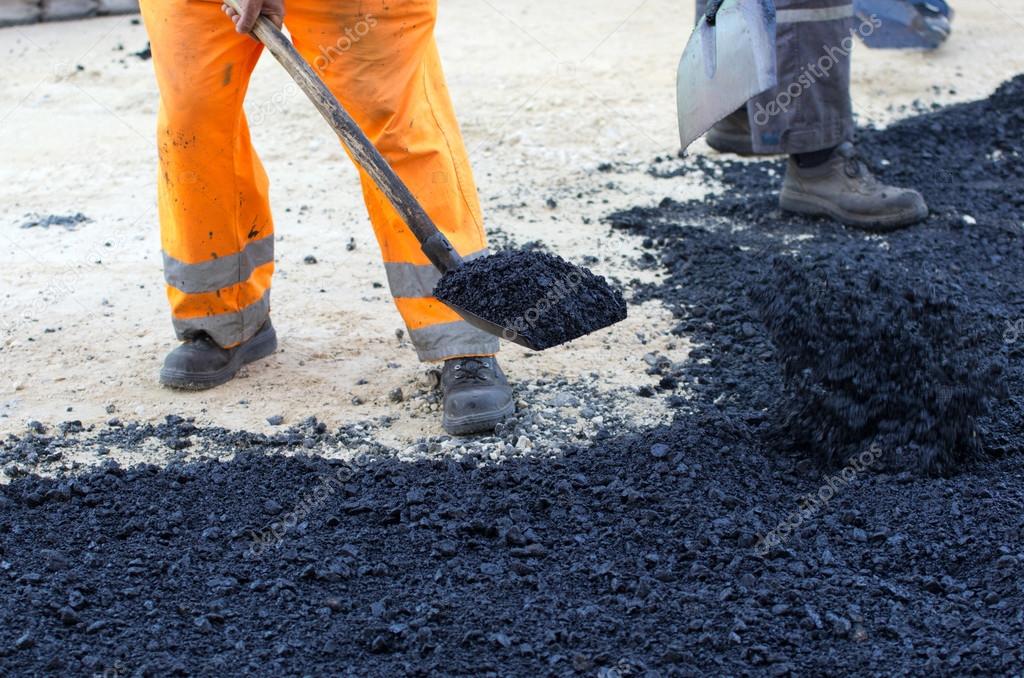 Worker with shovel on asphalt