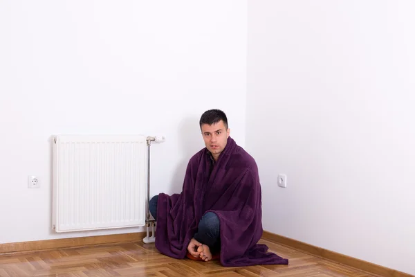 Человек с одеялом рядом с обогревателем — стоковое фото
