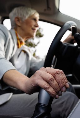 Araba süren yaşlı iş kadınının bulanık görüntüsü, vites koluna odaklan.