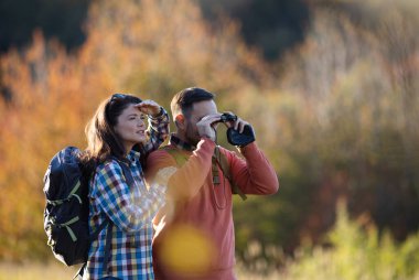 Birkaçı doğayı birlikte tecrübe ederken kuş gözlemciliği, renkli sonbahar yapraklarıyla çevrili, tek eşli dürbün kullanıyor..
