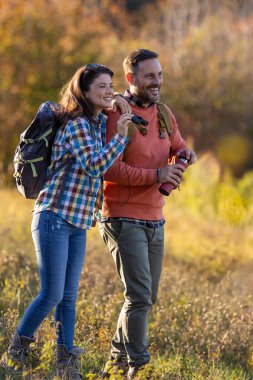 Birkaçı doğayı birlikte tecrübe ederken kuş gözlemciliği, renkli sonbahar yapraklarıyla çevrili, tek eşli dürbün kullanıyor..