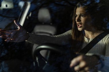 Bir kadın gece araba sürerken, elleriyle el kol hareketi yaparken gözle görülür şekilde üzgün olur. Dışardaki bir şeye tepki verirken ifadesi güçlü duygular gösteriyor..