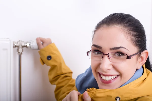 Mujer con chaqueta ajustando la calefacción Fotos De Stock