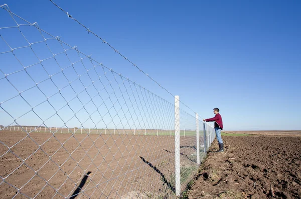 Homem segurando cerca de arame farpado — Fotografia de Stock