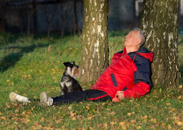 Homme âgé avec chien assis dans la forêt — Photo