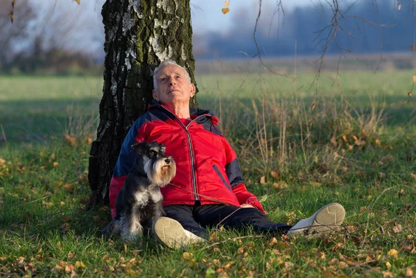 Äldre man med hund sitter i skogen — Stockfoto