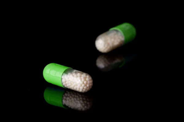 Green capsules on black background — Stock Photo, Image