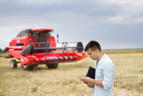 Affärsman med laptop och mobiltelefon på fältet — Stockfoto