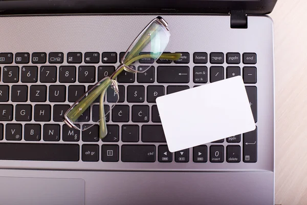 Laptop with blank business card and glasses — Stock Photo, Image