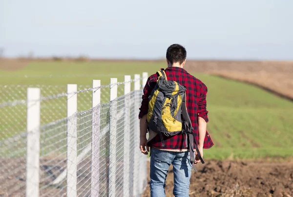 Man with back beside wire fence — Stock Photo, Image