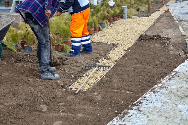 Workers installing flower beds with black earth and decorative stones. Concept of beautification of the garden. Selective focus. — Stock Image Workers Installing Flower Beds Black Earth Decorative Stones Concept Beautification Royalty Free Stock Photos