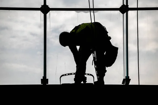 Worker silhouettes cleaning windows on height, cleaning building window glass. Cleaning windows from the inside.