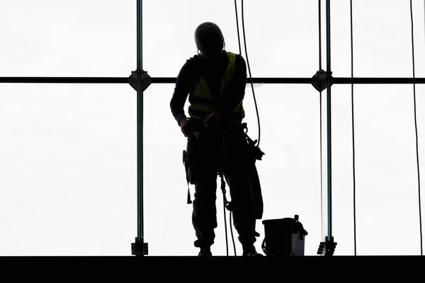 Worker silhouettes washing windows at heights, work with high risk