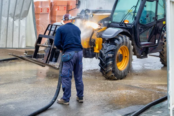 建設現場から出る前に建設機械を汚れから洗浄する労働者 高圧水洗浄 選択的焦点 — ストック写真