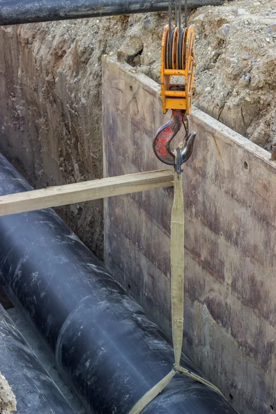 Crane hook hold up pipe in trench — Stock Photo, Image