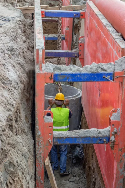 Worker setting concrete pipe in trench — Stock Photo, Image