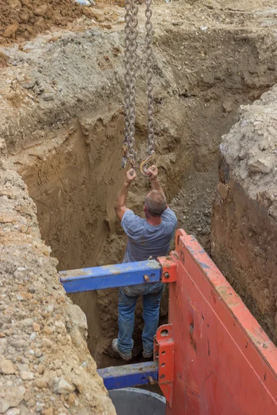 Trabajador de construcción de elevación de brazo de excavadora de trinchera en cadenas — Foto de Stock