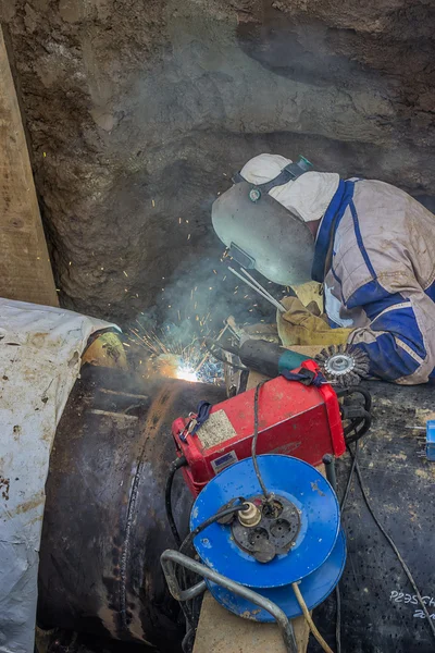 Welder welding heat pipes in trench — Stock Photo, Image
