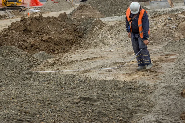 Construction worker measures the width of a new road lane — Stock Photo, Image