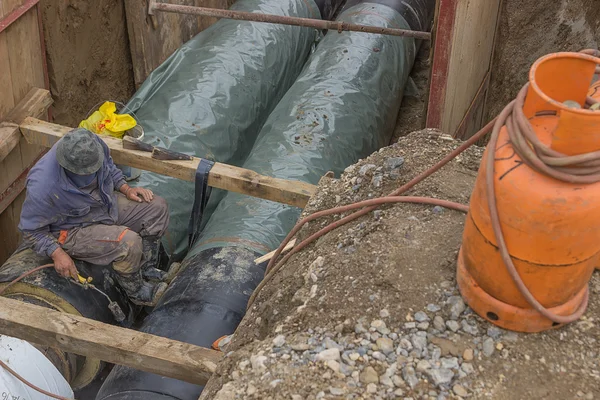 Insulation worker applied tar coating on underground heating pip — Stock Photo, Image